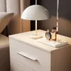 A close-up of a bedside table with a lamp and perfume bottles. Produktbild-Vorschau