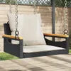 A black poly rattan hanging chair with beige cushions is shown outdoors, suspended by chains. Náhled obrázku produktu