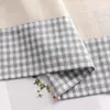 A close-up view of a fabric with a checkered pattern and a plain fabric. Produktbild-Vorschau