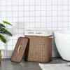 A laundry basket with its lid open, placed on a tiled floor next to a bathtub. Produktbild-Vorschau