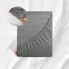 A fitted sheet is shown laid out on a bed, with a close-up inset showing hands tucking the sheet over a mattress corner. Produktbild-Vorschau