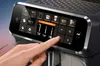 A hand is shown interacting with the touchscreen display of a coffee machine. Náhľad obrázku produktu