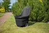 A black garden cart with two wheels sits on a green lawn next to a hedge. Podgląd zdjęcia produktu
