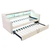 A beige upholstered daybed with a pull-out trundle bed underneath, shown against a white background. The daybed has a built-in shelf with LED lighting. Voir les images du produit