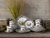 A collection of dinnerware and cups arranged on a wooden surface with dried grass and pinecones. Náhľad obrázku produktu