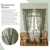 A room scene with green lace curtains hanging in a window, a small table with a lace tablecloth, and two chairs. Produktbild-Vorschau