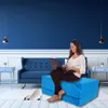 A woman sits on a blue foldable mattress in front of a blue sofa in a room with blue walls. Voir les images du produit