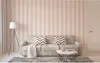 A living room scene with a sofa, coffee table, and lamp, showcasing striped wallpaper. Produktbild-Vorschau