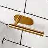 A gold-colored toilet paper holder mounted on a white tiled wall. Produktbild-Vorschau