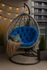 A hanging egg chair with a blue cushion and a brown throw blanket on a balcony. Anteprima dell’immagine prodotto