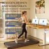 A woman is using a treadmill in front of a standing desk. Produktbild-Vorschau