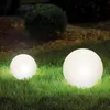 Two illuminated spherical garden lights on a lawn at night.