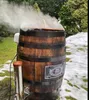 A wooden barrel smoker with steam coming out of the top, set up outdoors in a snowy garden. Náhled obrázku produktu