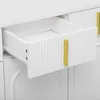 A close-up view of a white sideboard drawer with a gold handle, showing the ribbed texture of the drawer front. Produktbild-Vorschau