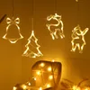 Christmas-themed LED lights in the shape of a bell, Christmas tree, and reindeer are hanging in front of a chair. Podgląd zdjęcia produktu