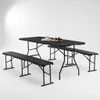 A black folding table and two benches are set up on a white background, with a plate of pastries and a cup on the table. Produktbild-Vorschau