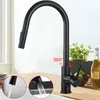 A black kitchen faucet with a pull-down sprayer is shown in a kitchen setting, with inset images demonstrating water flow and spray patterns. A plant and bottles are visible in the background. Produktbild-Vorschau