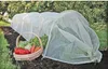 A garden tunnel made of white mesh is set up over a garden bed, with a basket of fresh vegetables placed in front of it. Produktbild-Vorschau