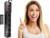 A woman is pointing upwards next to a power strip with a remote control. Produktbild-Vorschau