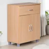 A light brown wooden sideboard with a drawer and two doors, standing on gray legs, against a white wall and next to a window with curtains and a plant. Náhľad obrázku produktu