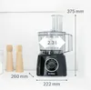 A black Bosch food processor is shown on a white shelf with two wooden salt and pepper grinders next to it. Dimensions are indicated with lines and text. Produktbild-Vorschau