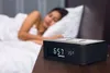 A woman sleeping in bed with a digital alarm clock on a nightstand in the foreground. Produktbild-Vorschau