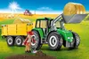 A toy tractor with a trailer and a figure in a farm setting. Voir les images du produit