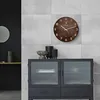 A modern living room with a wooden wall clock and a cabinet. Voir les images du produit