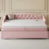 A pink upholstered daybed with a tufted headboard and a pull-out trundle bed is shown in a room with decorative wall molding. Produktbild-Vorschau