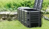 A black compost bin with its lid open, situated in a grassy garden with ferns and a stone wall in the background. Náhled obrázku produktu