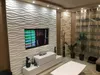 A living room with a TV mounted on a decorative wave-patterned wall panel. Podgląd zdjęcia produktu