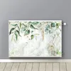 A decorative radiator cover with a botanical leaf and gold accent design, shown mounted on a gray wall above a wooden floor. Voir les images du produit