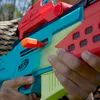A close-up shot of a person holding a colorful toy gun. Produktbild-Vorschau