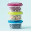 A stack of three clear plastic food containers with colored lids, each filled with different food items. Náhled obrázku produktu