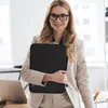 A woman in a business suit holds a black laptop sleeve. Produktbild-Vorschau