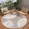 A round rug with a mandala pattern on a wooden deck with two chairs and a coffee table.