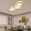A modern living room with a sectional sofa, coffee table, and artwork on the wall, illuminated by a contemporary ceiling light. Produktbild-Vorschau