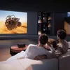 A family is watching a movie on a projector screen in a dimly lit living room. Anteprima dell’immagine prodotto