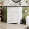 A white bathroom vanity with drawers and a cabinet is shown in a bathroom setting with green tiled walls and floral wallpaper. Podgląd zdjęcia produktu