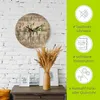 A wall clock with a floral design is displayed on a white brick wall, with decorative items on a table below. A green sidebar highlights product features. Produktbild-Vorschau