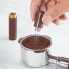 A hand is using a coffee distributor tool with needles to distribute coffee grounds in an espresso portafilter. Produktbild-Vorschau