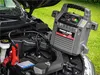 A car battery jump starter is connected to a car battery under the hood of a car. Anteprima dell’immagine prodotto