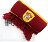 A Harry Potter Gryffindor scarf with a crest and fringe, lying on a white surface with some text. Náhled obrázku produktu
