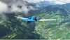 A blue airplane flying over a green, mountainous landscape with clouds. Náhľad obrázku produktu