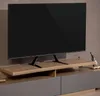 A black TV is mounted on a wooden stand, which is placed on a gray cabinet. The background is a textured brown wall. Náhled obrázku produktu
