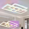 A modern, multi-tiered rectangular LED ceiling light fixture with integrated RGB color-changing LEDs, shown illuminated with various colors against a white ceiling. Produktbild-Vorschau