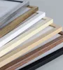 A close-up, angled view of several picture frames stacked on top of each other, showcasing different colors and wood grain textures. Produktbild-Vorschau