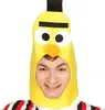 A man wearing a yellow banana-shaped hat with a black stem and black eyes and a small orange nose. He is smiling and looking at the camera. He is wearing a striped shirt with red, black, and white stripes. Produktbild-Vorschau