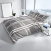 A bed with plaid bedding in a modern room with a large window. Produktbild-Vorschau