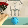 A blue octopus-shaped bathtub overflow drain cover is shown in a bathtub with a faucet and roses. Produktbild-Vorschau